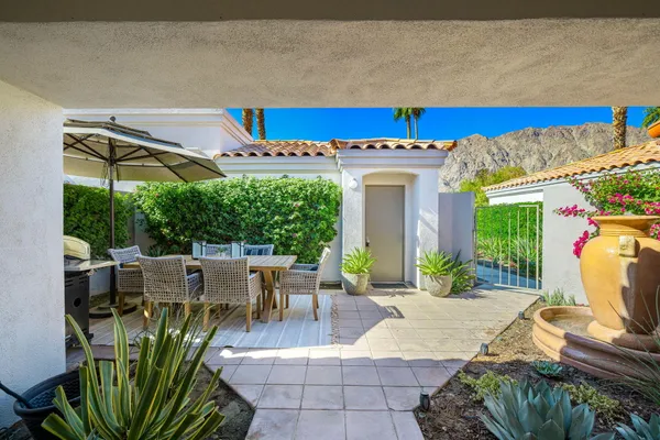 a view of a patio with table and chairs potted plants and large tree