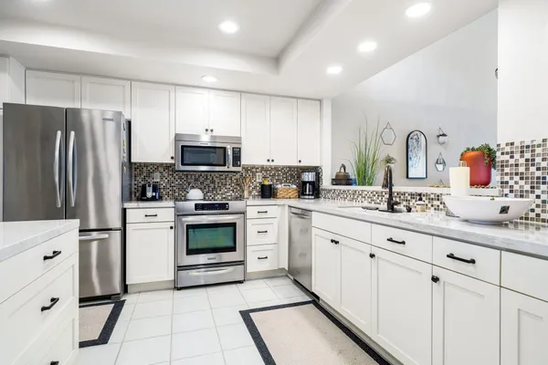 a kitchen with granite countertop white cabinets and stainless steel appliances