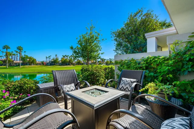 a view of a patio with table and chairs potted plants and a palm tree