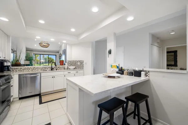 a kitchen with white cabinets appliances and kitchen island