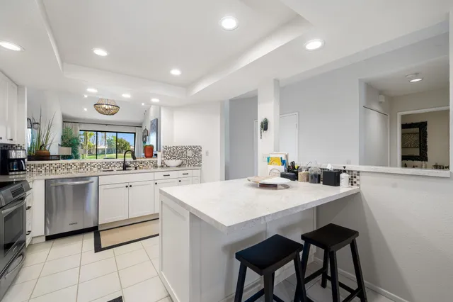 a kitchen with white cabinets appliances and kitchen island