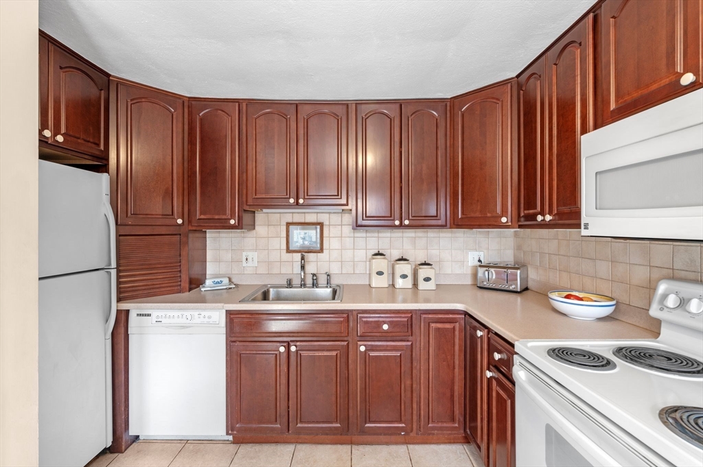 68 Preston Street, Unit 9D Wakefield, MA 01880 - Photo 12 of 29 a kitchen with a sink a refrigerator and cabinets
