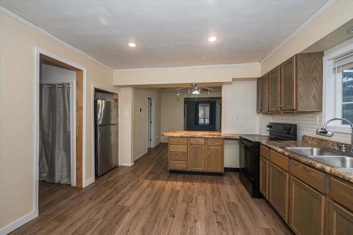 3701 East 2nd Street Superior, WI 54880 - Photo 8 of 25 Kitchen with a peninsula, black electric range, dishwasher, refrigerator, vinyl plank flooring, and ornamental molding