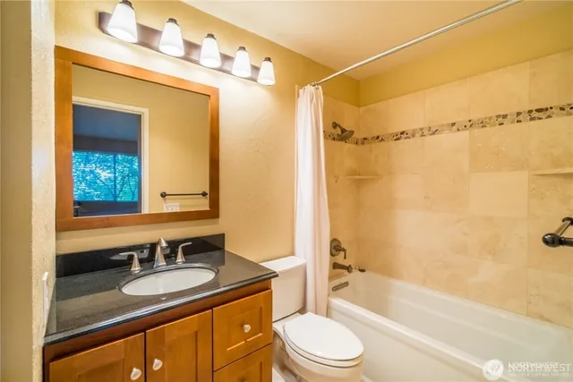 a bathroom with a granite countertop sink toilet mirror and bathtub