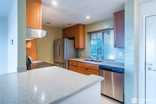 a kitchen with stainless steel appliances kitchen island granite countertop a sink refrigerator and cabinets