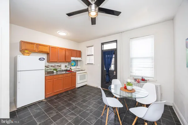 a kitchen with stainless steel appliances kitchen island granite countertop a refrigerator a sink dishwasher a dining table and chairs with wooden floor
