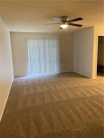 an empty room with a ceiling fan and bathroom view