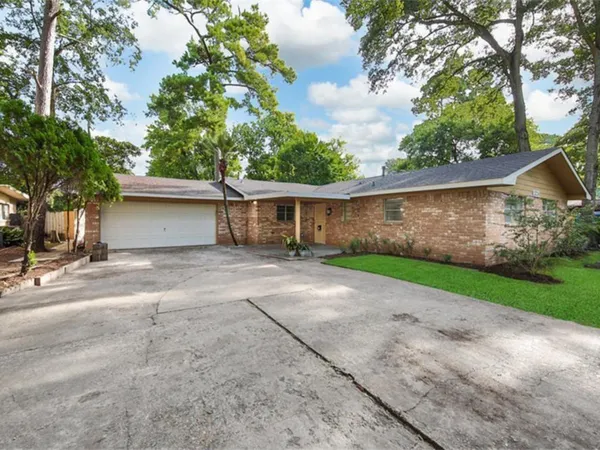 a view of a house with a yard and a large tree