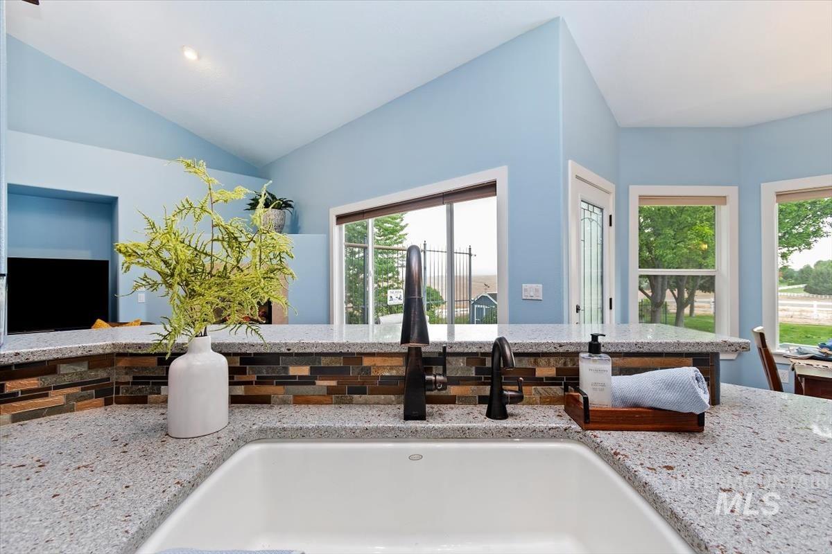 10462 West Lanktree Gulch Road Star, ID 83669 - Photo 10 of 48 Kitchen island with an undermount sink, a multi-tone tile backsplash, and speckled countertops