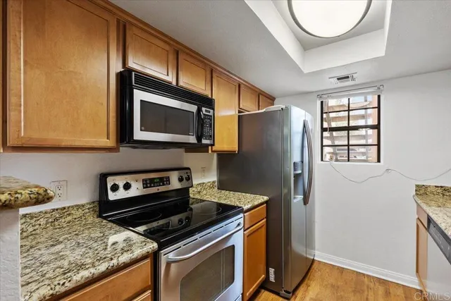 a kitchen with stainless steel appliances granite countertop a refrigerator and a stove top oven