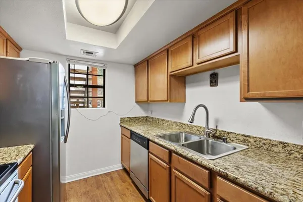 a kitchen with stainless steel appliances granite countertop a sink a stove and a wooden cabinets