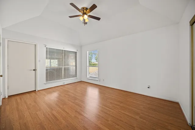 a view of an empty room with a window and wooden floor