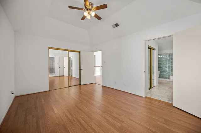 a view of empty room with wooden floor and fan