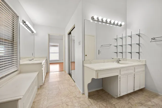 a spacious bathroom with a double vanity sink a large mirror and a bathtub