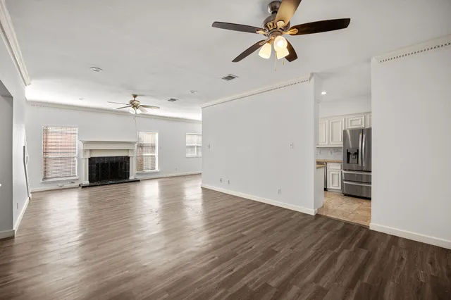an empty room with wooden floor fireplace and ceiling fan