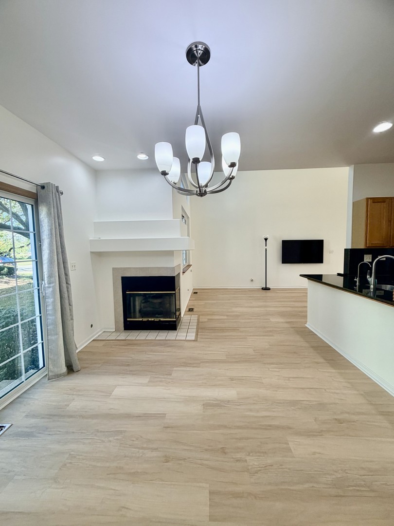 4 Haverton Court Streamwood, IL 60107 - Photo 5 of 30 a view of a livingroom with a fireplace a chandelier and wooden floor