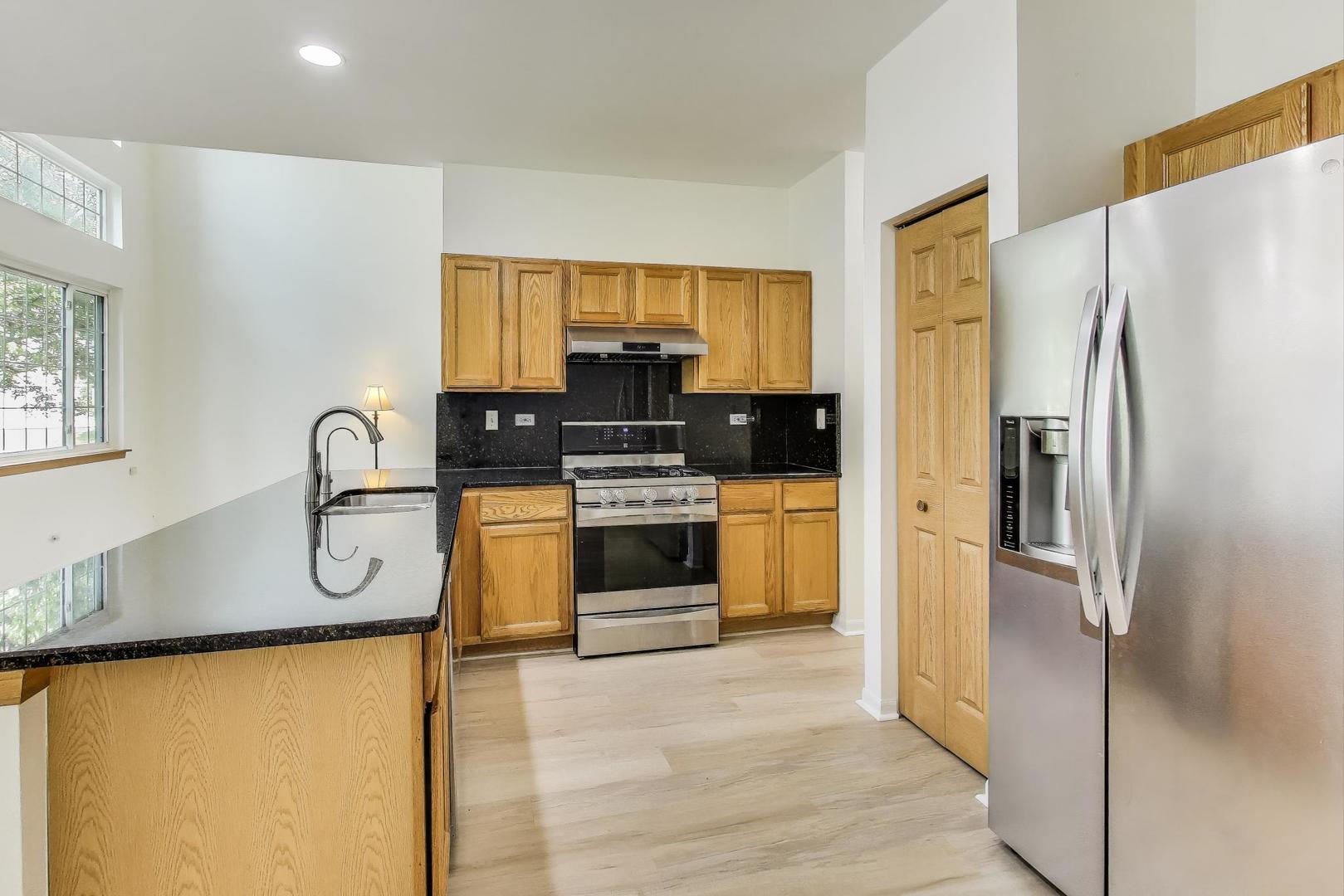 4 Haverton Court Streamwood, IL 60107 - Photo 8 of 30 a kitchen with stainless steel appliances granite countertop a refrigerator a stove and a sink with wooden floor