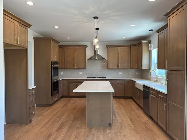 a large kitchen with granite countertop a large counter top a sink stainless steel appliances and cabinets