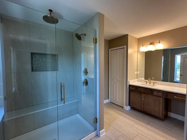 a bathroom with a double vanity sink a toilet and shower