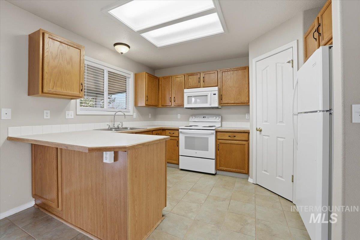3273 North Chatterton Way Boise, ID 83713 - Photo 10 of 29 Kitchen with white appliances, light countertops, a peninsula, a breakfast bar area, and light tile patterned flooring