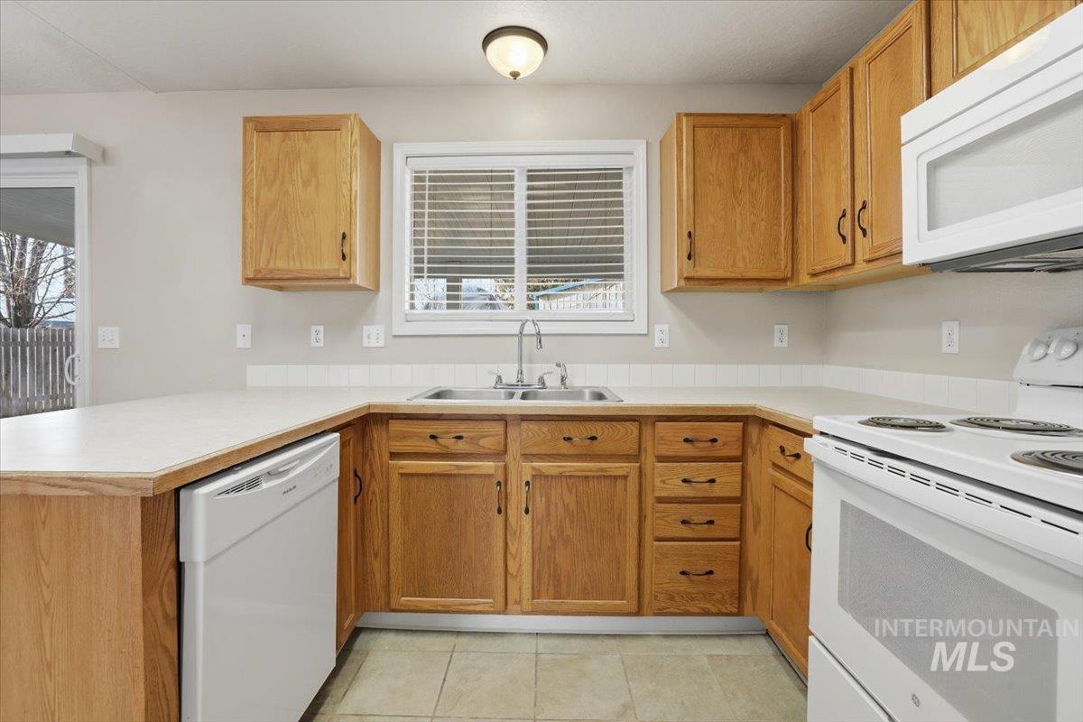 3273 North Chatterton Way Boise, ID 83713 - Photo 12 of 29 Kitchen with white appliances, light countertops, healthy amount of natural light, and a peninsula