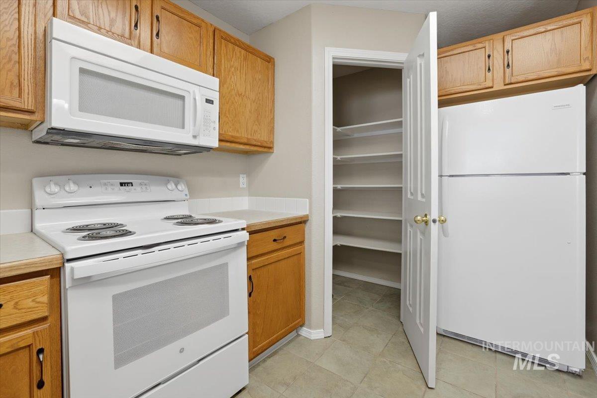 3273 North Chatterton Way Boise, ID 83713 - Photo 13 of 29 Kitchen featuring white appliances, light countertops, light tile patterned flooring, and wood finish cabinetry