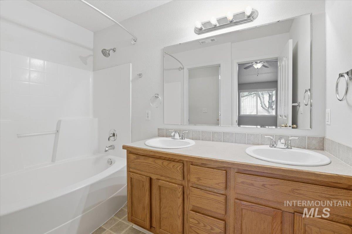 3273 North Chatterton Way Boise, ID 83713 - Photo 19 of 29 Full bathroom featuring washtub / shower combination, double vanity, light tile patterned floors, and a ceiling fan