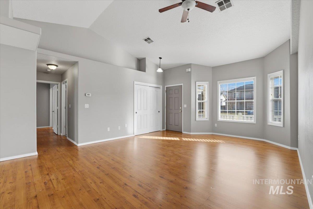 3273 North Chatterton Way Boise, ID 83713 - Photo 4 of 29 Unfurnished living room featuring light wood finished floors, lofted ceiling, and ceiling fan