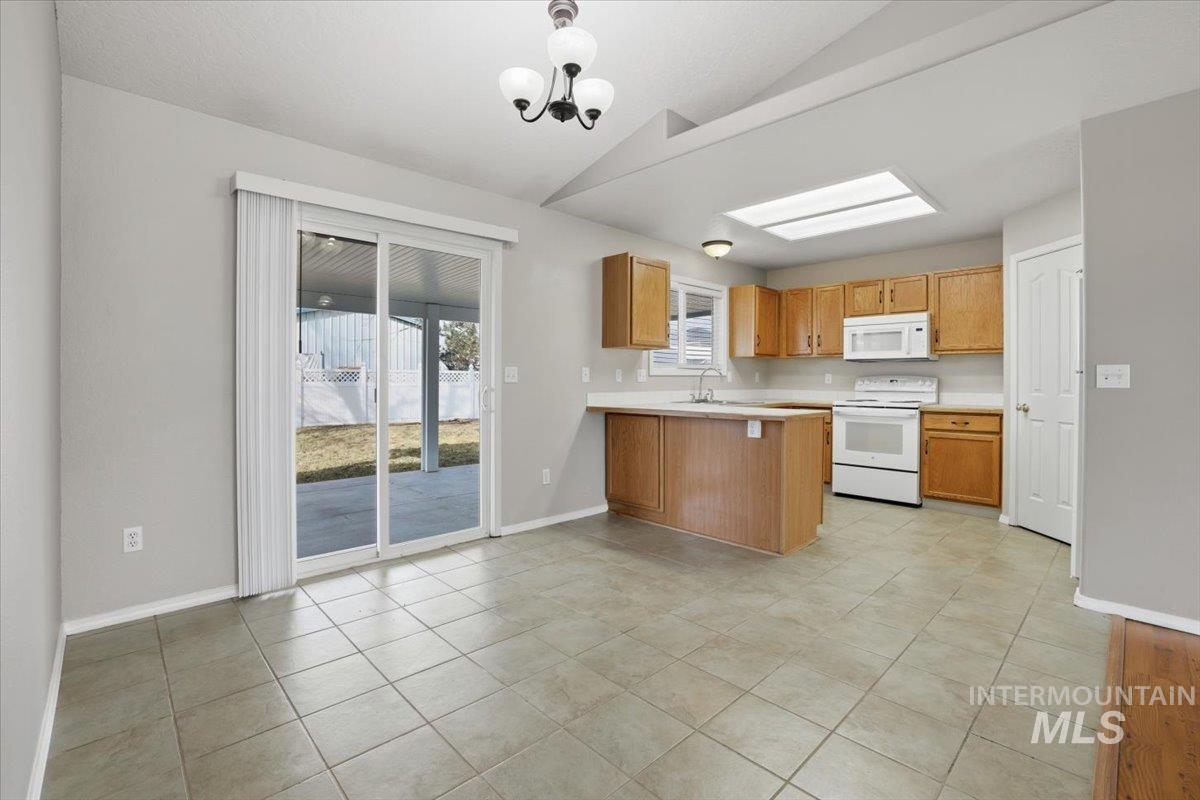 3273 North Chatterton Way Boise, ID 83713 - Photo 9 of 29 Kitchen with light countertops, white appliances, a peninsula, vaulted ceiling, and light tile patterned flooring