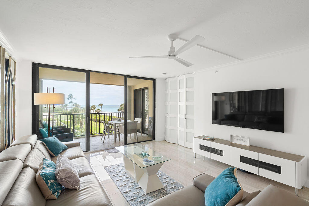 300 Ocean Trail Way, Unit 301 Jupiter, FL 33477 - Photo 12 of 64 a living room with furniture a flat screen tv and a floor to ceiling window