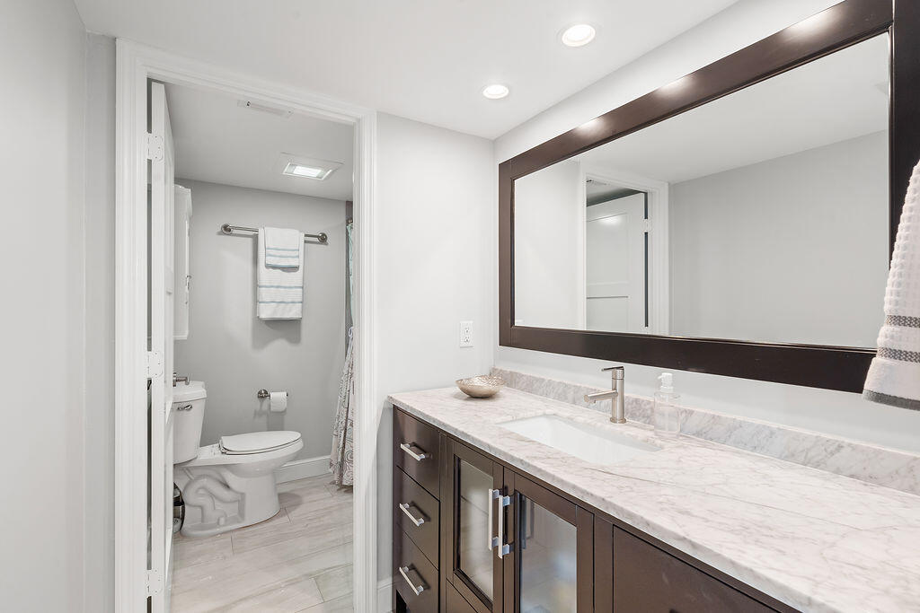 300 Ocean Trail Way, Unit 301 Jupiter, FL 33477 - Photo 34 of 64 a bathroom with a granite countertop sink a toilet and a large mirror