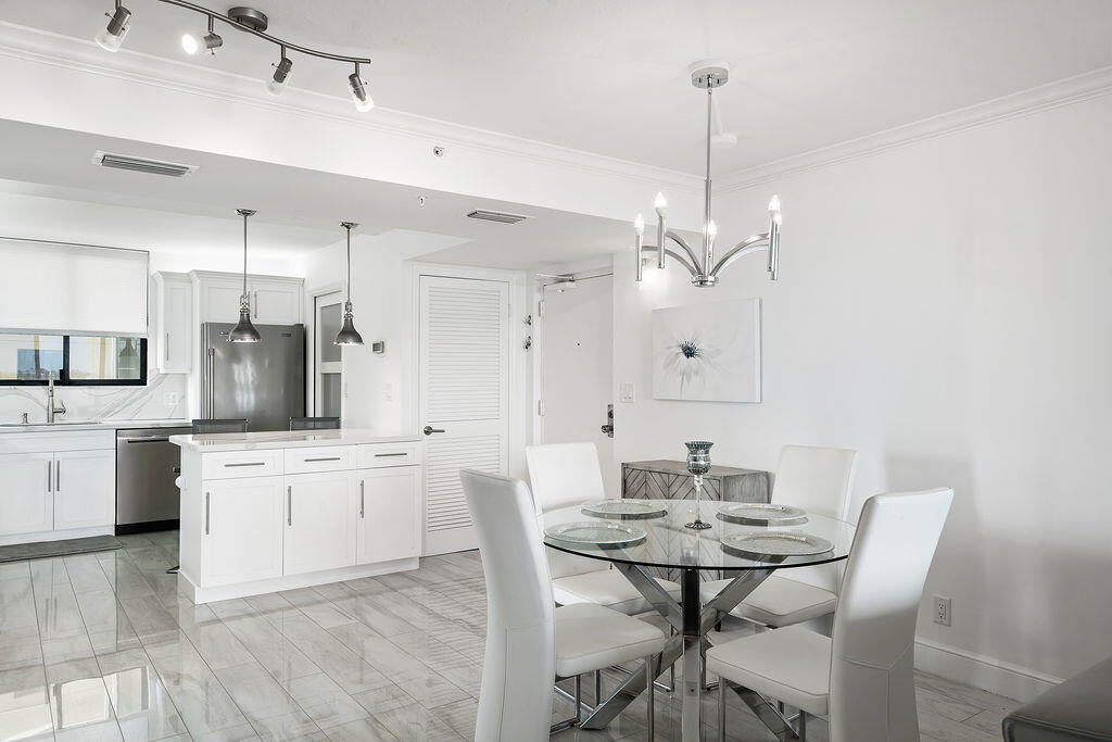 300 Ocean Trail Way, Unit 301 Jupiter, FL 33477 - Photo 9 of 64 a kitchen with stainless steel appliances kitchen island granite countertop a table chairs and white cabinets