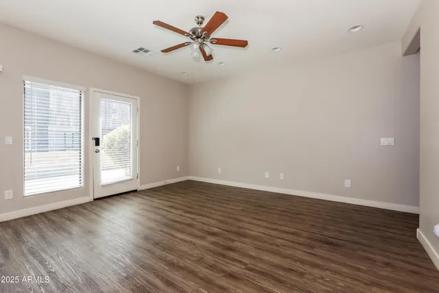 a view of an empty room with wooden floor and a window