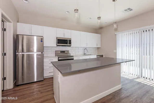 a kitchen with kitchen island granite countertop a sink appliances and cabinets