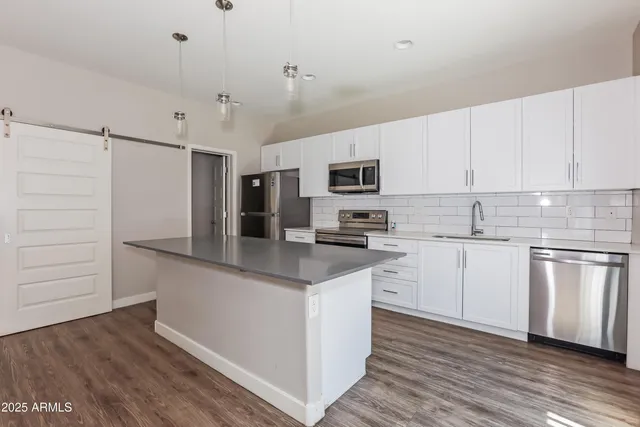a kitchen with granite countertop a sink cabinets stainless steel appliances and wooden floor