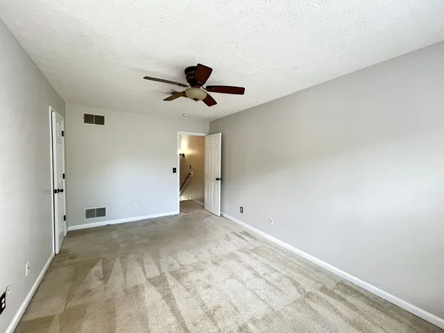 a view of an empty room and chandelier fan