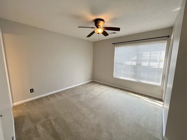 an empty room with windows and fan