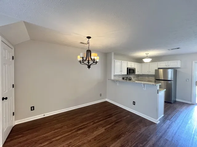 a view of kitchen and empty room with wooden floor