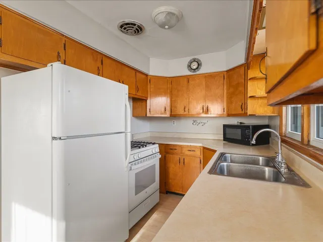 a kitchen with stainless steel appliances a refrigerator a sink a stove and white cabinets with wooden floor