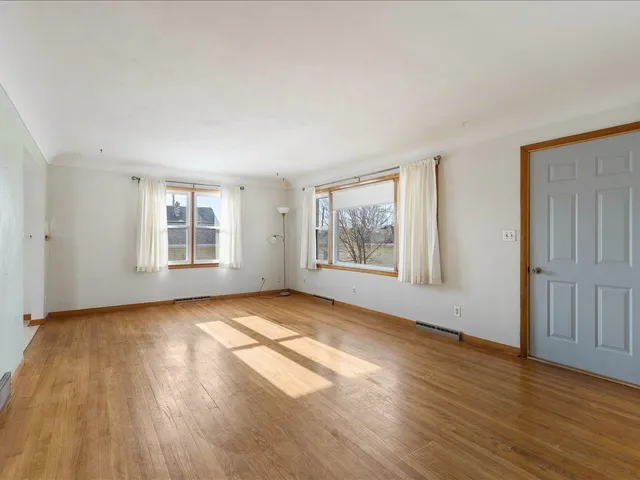a view of an empty room with wooden floor and windows