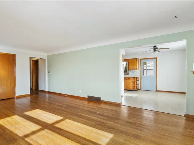 a view of an empty room with window and wooden floor