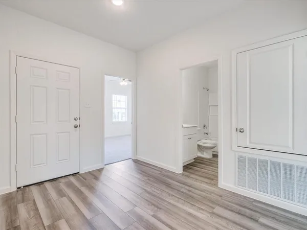 an empty room with wooden floor and bathroom