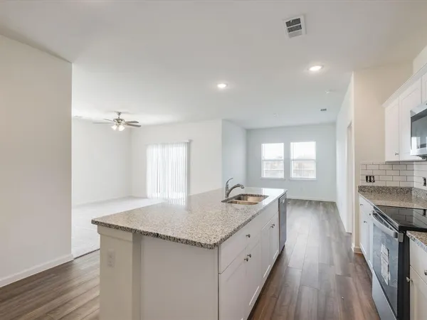 a kitchen with granite countertop a sink stove and cabinets