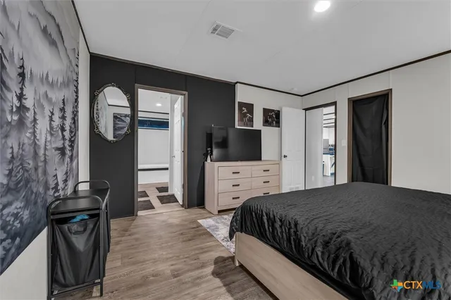 a bedroom with a bed and a flat tv screen on dresser