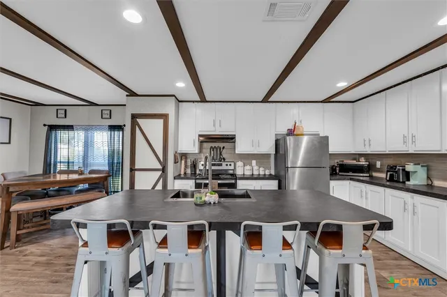 a kitchen with stainless steel appliances a dining table chairs and granite counter tops