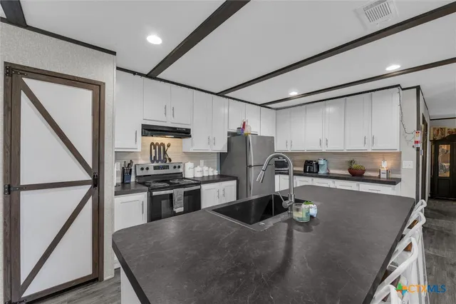 a kitchen with stainless steel appliances granite countertop a sink a stove and a refrigerator