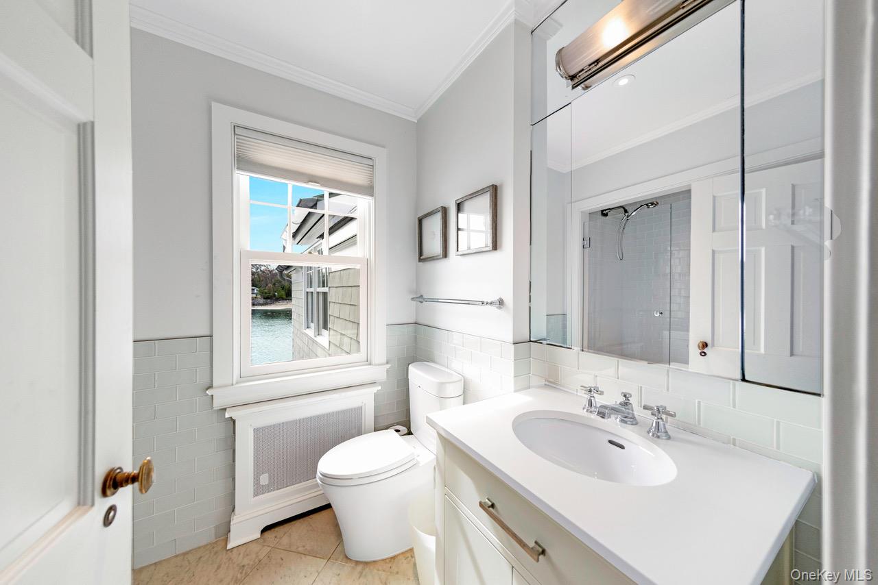 6 Pine Island Road Rye, NY 10580 - Photo 23 of 38 a bathroom with a toilet a sink a mirror and a window
