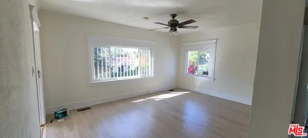 a view of an empty room with a window and wooden floor
