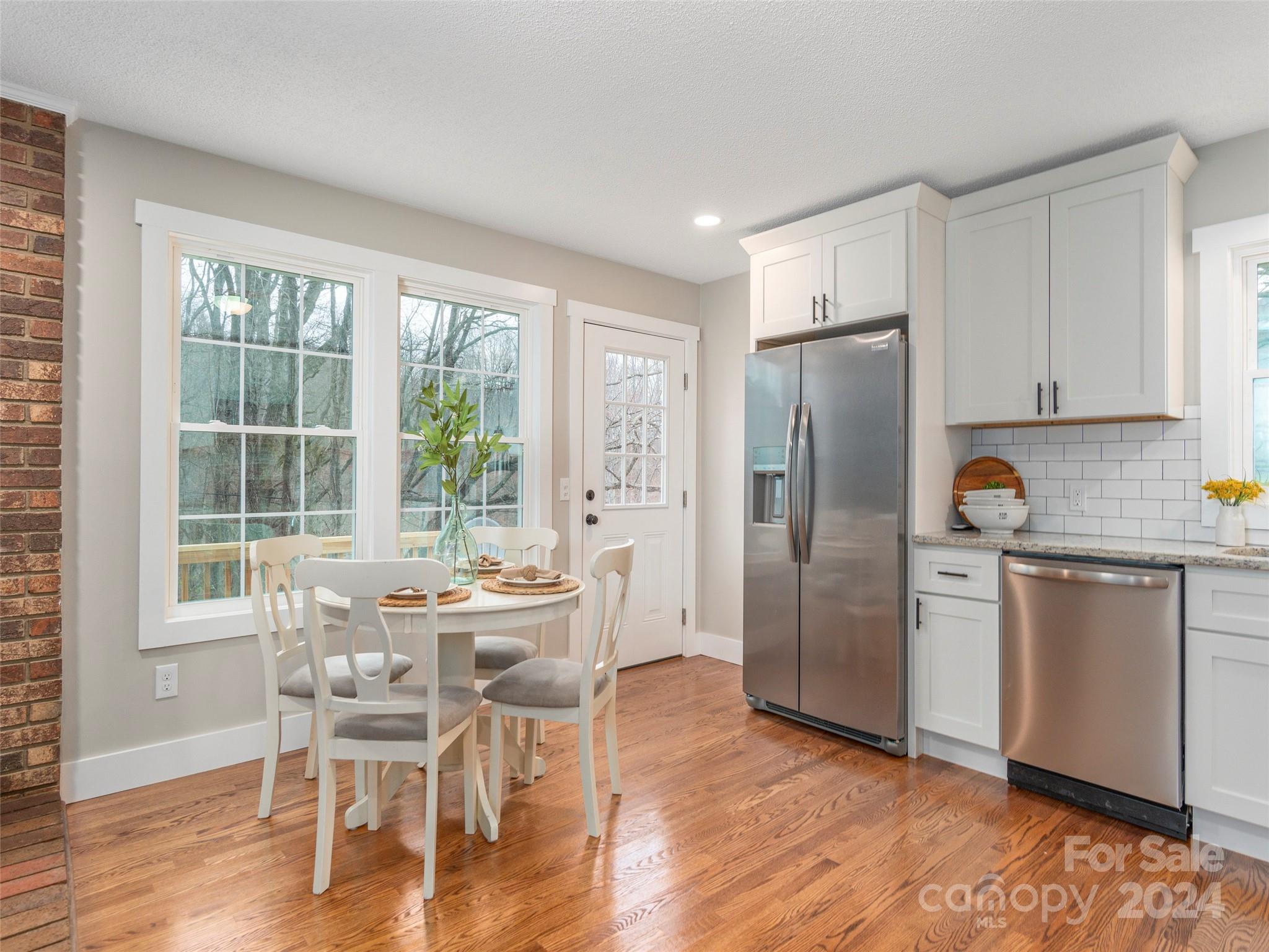 65 Squaw Ridge Road Waynesville, NC 28786 - Photo 11 of 24 a kitchen with stainless steel appliances a dining table chairs refrigerator and cabinets