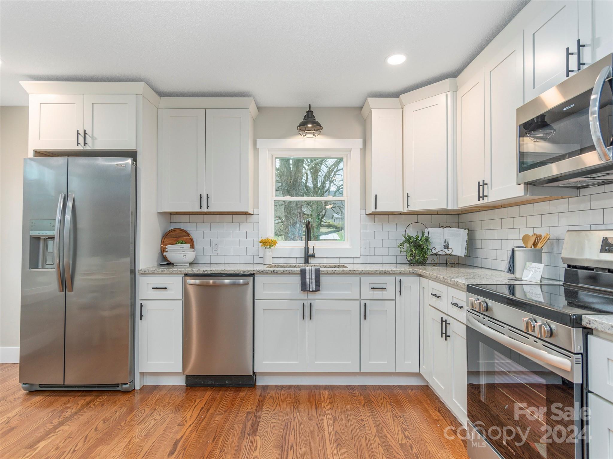 65 Squaw Ridge Road Waynesville, NC 28786 - Photo 4 of 24 a kitchen with stainless steel appliances a sink cabinets and wooden floor